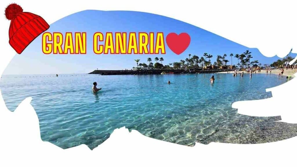 Gran Canaria in inverno: si fa il bagno a Gran Canaria a gennaio? 6 Immagine di copertina con un berretto di lana invernale rosso su una scena di spiaggia a Gran Canaria, acqua turchese e persone che fanno il bagno.