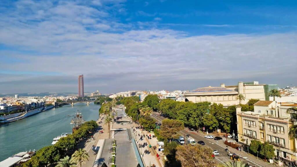 Consigli per Noleggiare un'Auto a Siviglia: La Tua Guida Completa 4 Noleggiare un'Auto a Siviglia. Vista panoramica di Siviglia con il fiume Guadalquivir, la Torre del Oro, il Paseo de Cristóbal Colón e l'edificio del Palazzo di San Telmo.
